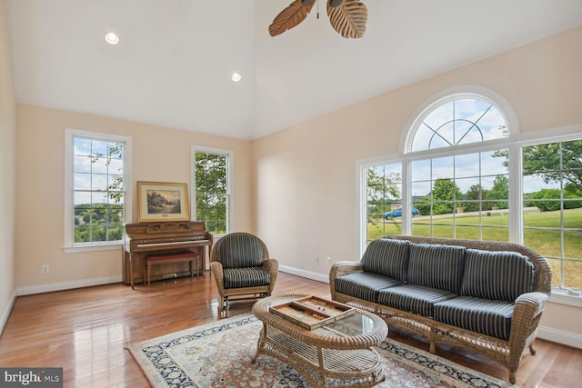 living room with a healthy amount of sunlight, vaulted ceiling, light wood-style flooring, and baseboards