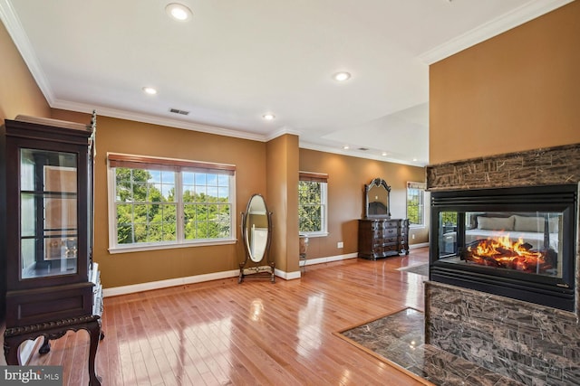 interior space featuring light wood-style flooring, recessed lighting, a fireplace, baseboards, and crown molding