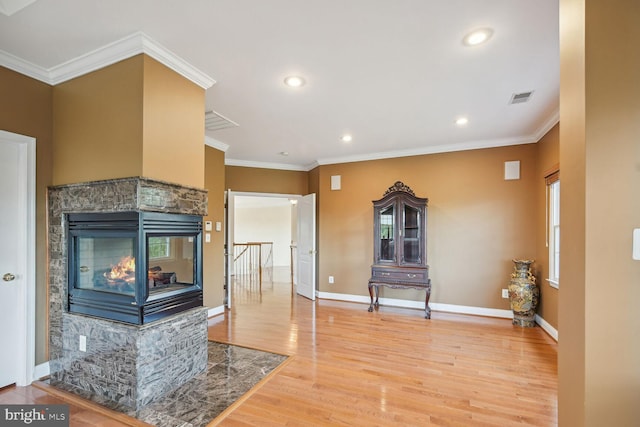 living room featuring ornamental molding, visible vents, baseboards, and wood finished floors