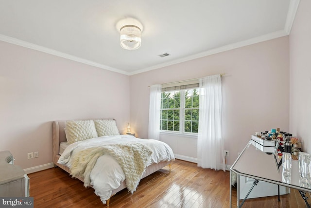 bedroom featuring ornamental molding, wood finished floors, and baseboards