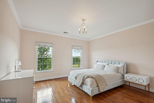 bedroom with baseboards, ornamental molding, wood finished floors, and an inviting chandelier