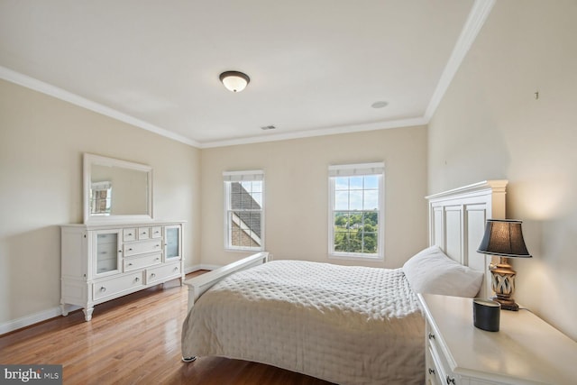 bedroom with light wood finished floors, baseboards, visible vents, and crown molding