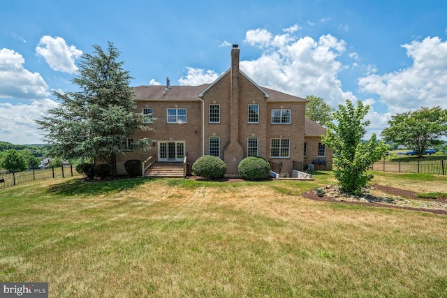 back of property featuring fence, a chimney, and a lawn