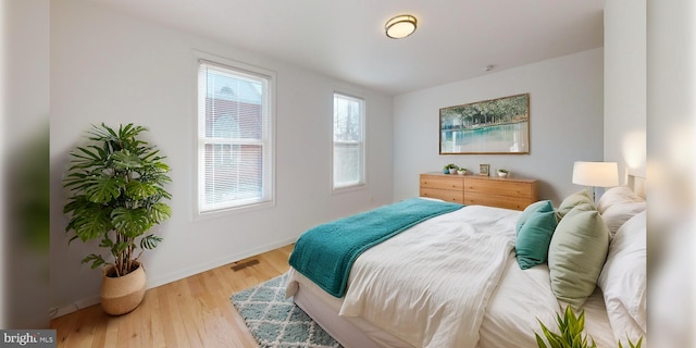 bedroom featuring visible vents, baseboards, and wood finished floors