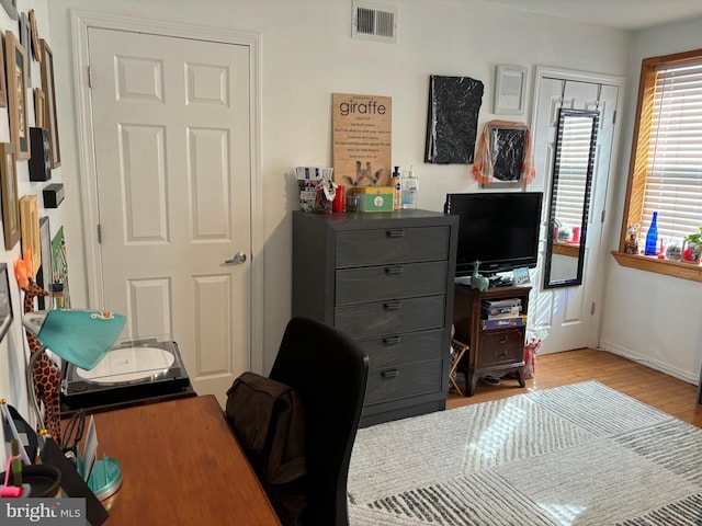 office space with light wood-style flooring, visible vents, and baseboards