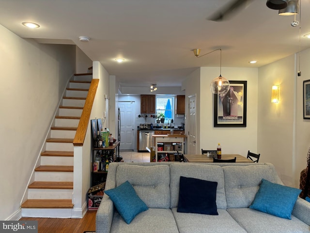 living area with light wood-type flooring, stairs, and baseboards