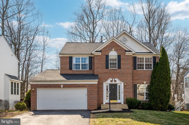 view of front of house featuring driveway, brick siding, a front lawn, and roof with shingles