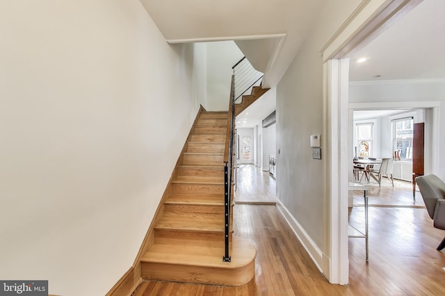 stairs with baseboards, crown molding, and hardwood / wood-style floors