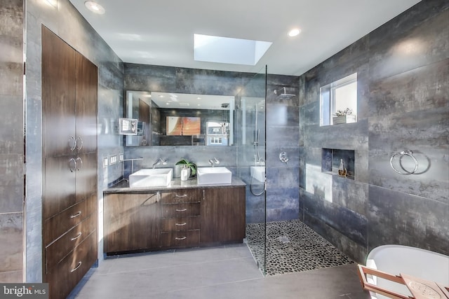 full bathroom with a skylight, a sink, tile walls, and walk in shower