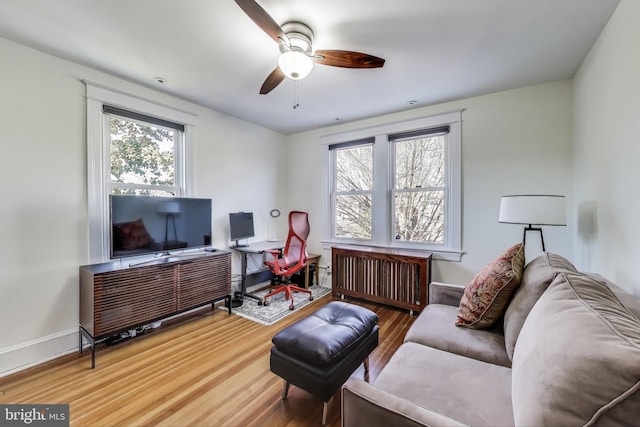 office space featuring baseboards, plenty of natural light, radiator heating unit, and wood finished floors