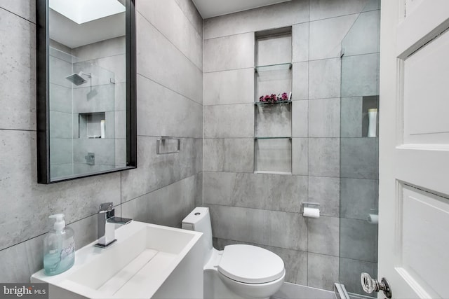 bathroom with a sink, toilet, and tile walls