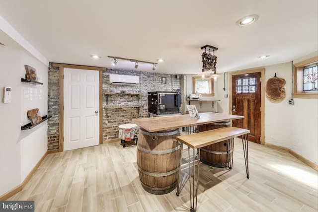 kitchen with an AC wall unit, light wood finished floors, a wealth of natural light, and baseboards