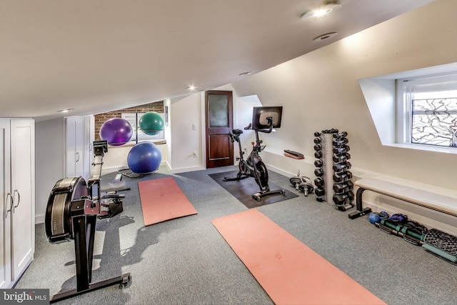 workout room featuring lofted ceiling and baseboards