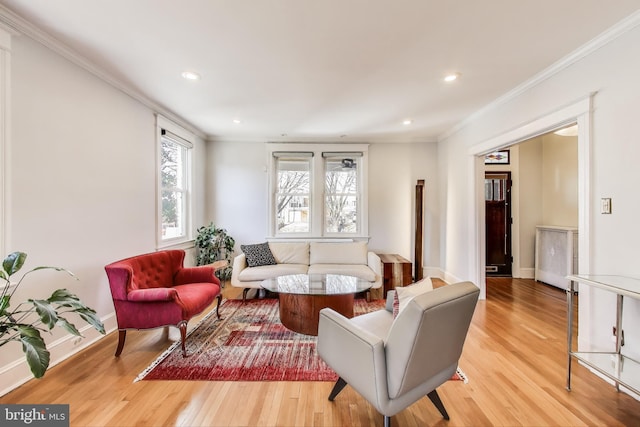 living area featuring crown molding, light wood-style flooring, and baseboards