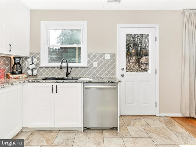 kitchen with a sink, white cabinets, stainless steel dishwasher, light stone countertops, and tasteful backsplash