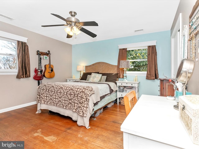 bedroom featuring light wood-style flooring, a ceiling fan, visible vents, and baseboards