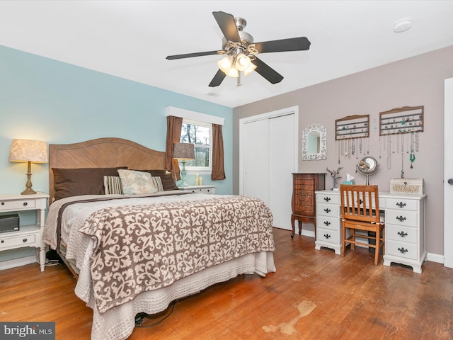 bedroom featuring ceiling fan, visible vents, a closet, and wood finished floors