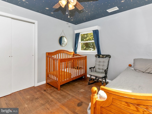 bedroom with a closet, wood finished floors, and visible vents