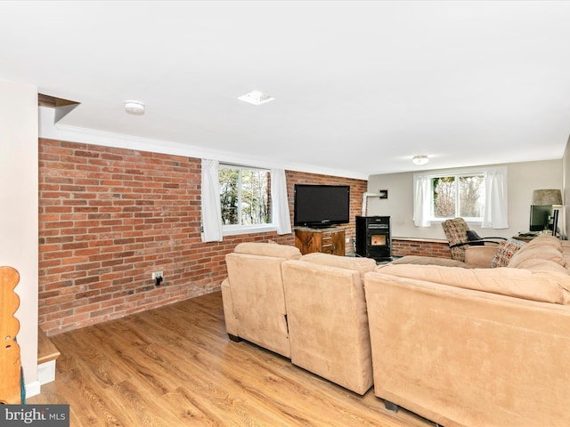 living area featuring brick wall, a wood stove, and light wood-style floors