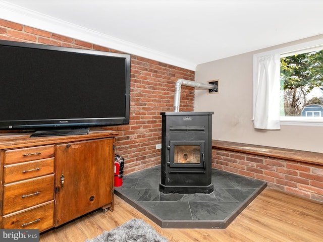 room details featuring a fire extinguisher, a wood stove, crown molding, and wood finished floors