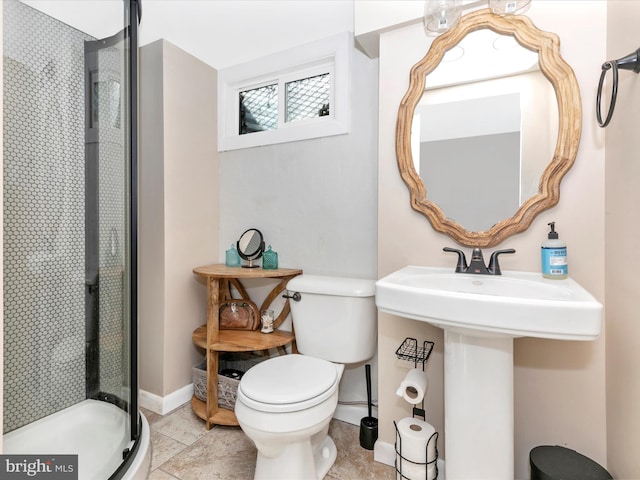 bathroom with toilet, a stall shower, and baseboards