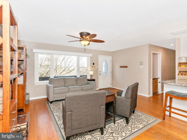 living room featuring a ceiling fan, light wood-style flooring, and baseboards