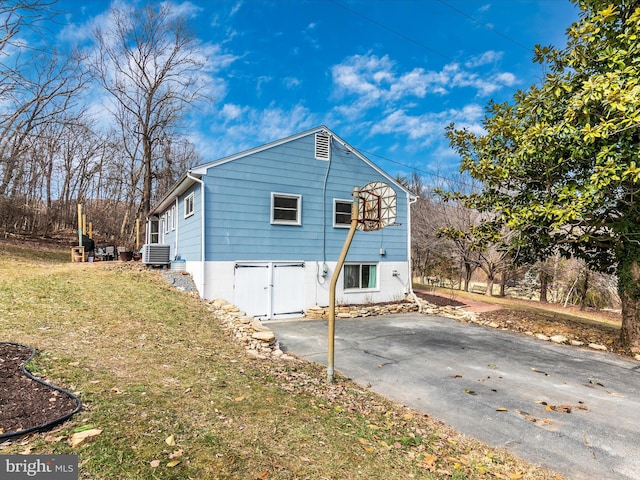 view of home's exterior with central AC, a yard, and driveway