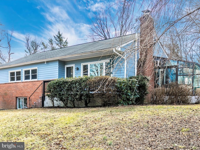 view of front of house with brick siding, a chimney, and a front yard