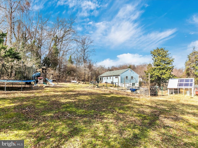 view of yard featuring an outbuilding, a trampoline, and a playground