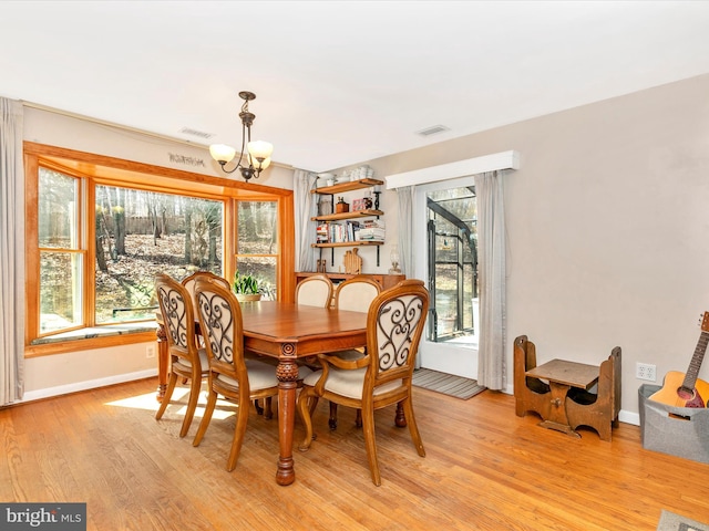 dining space featuring light wood-type flooring, visible vents, baseboards, and an inviting chandelier