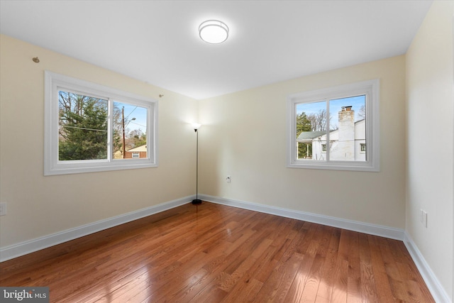 spare room with light wood-style floors, plenty of natural light, and baseboards