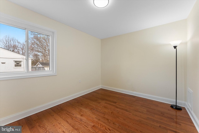 spare room featuring baseboards and wood finished floors