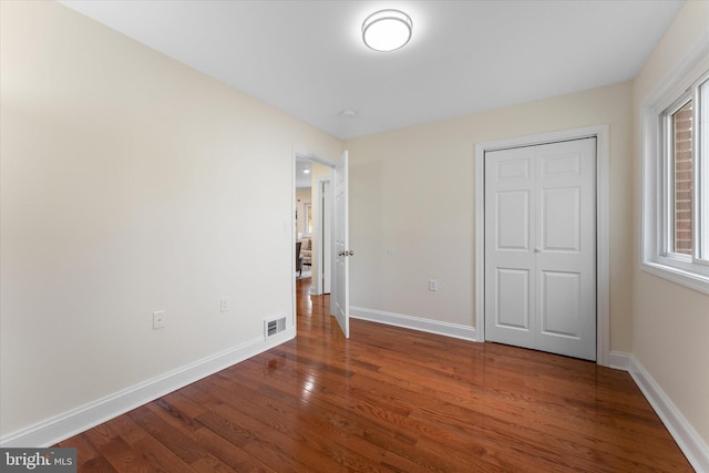 unfurnished bedroom featuring wood finished floors, visible vents, and baseboards