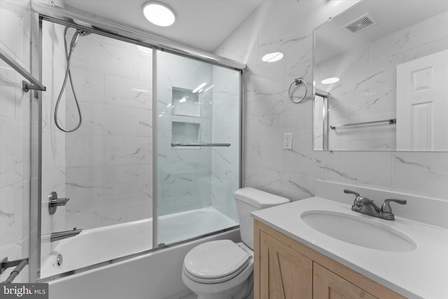 bathroom featuring visible vents, toilet, shower / bath combination with glass door, vanity, and tile walls