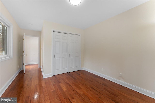 unfurnished bedroom with a closet, baseboards, and wood finished floors