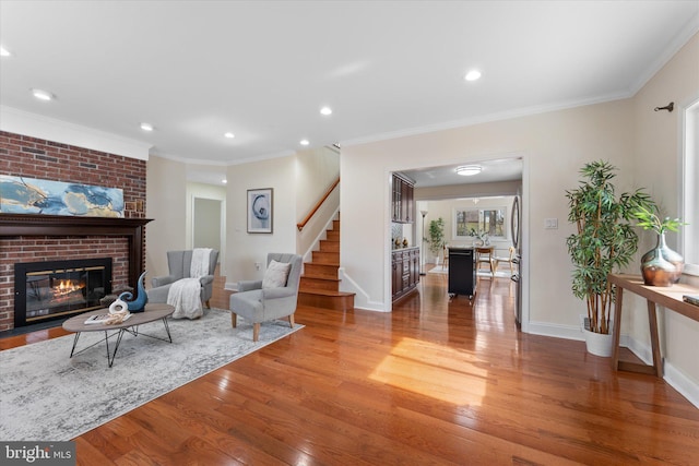 living room with light wood finished floors, a fireplace, stairway, and ornamental molding