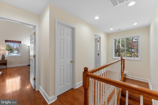 hallway featuring a healthy amount of sunlight, visible vents, hardwood / wood-style floors, and an upstairs landing