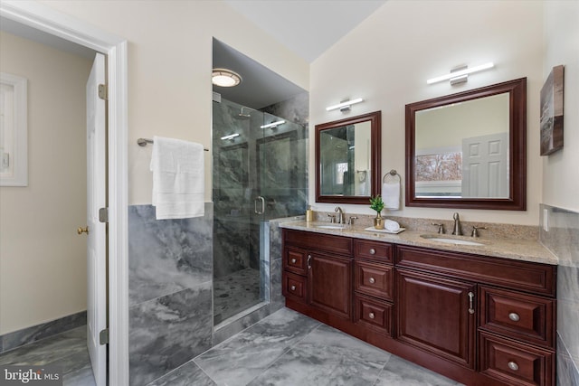 full bath featuring a stall shower, marble finish floor, a sink, and double vanity