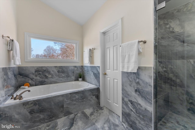 bathroom featuring a stall shower, lofted ceiling, a bath, marble finish floor, and tile walls