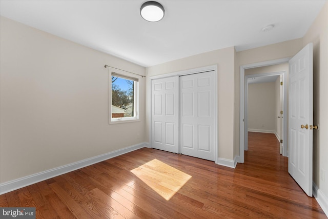 unfurnished bedroom featuring a closet, wood finished floors, and baseboards