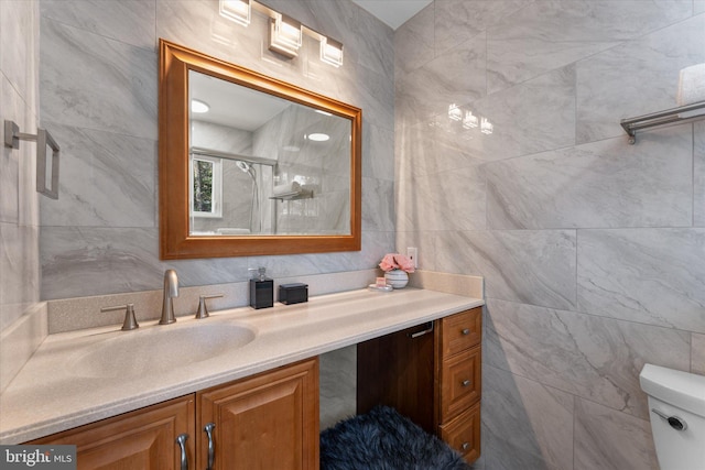 bathroom with tile walls, vanity, and a shower stall