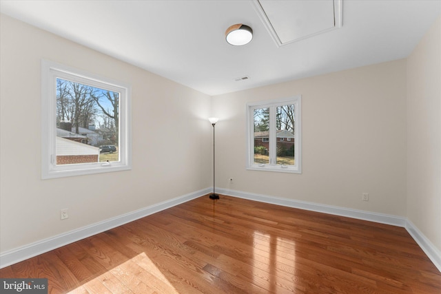 unfurnished room featuring visible vents, baseboards, and wood finished floors