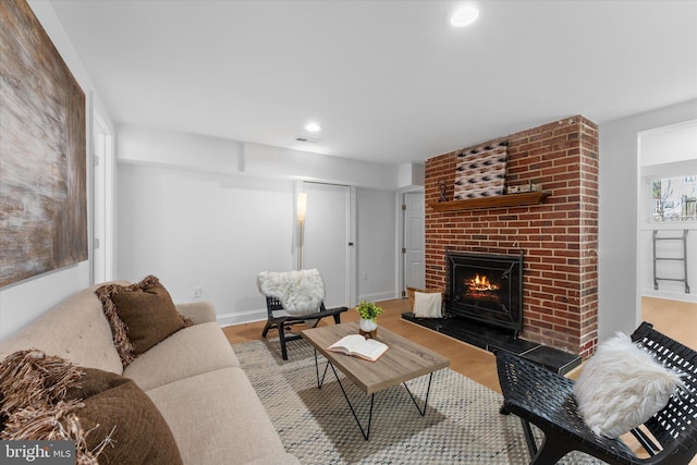 living room with recessed lighting, visible vents, a brick fireplace, wood finished floors, and baseboards