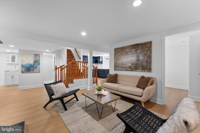 living area with light wood-type flooring, baseboards, stairway, and recessed lighting