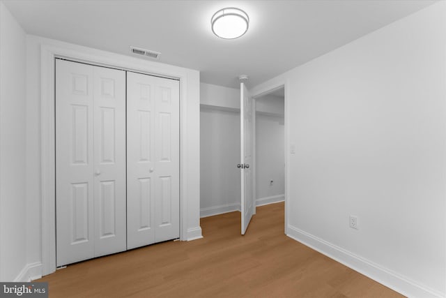 unfurnished bedroom with a closet, visible vents, baseboards, and light wood finished floors