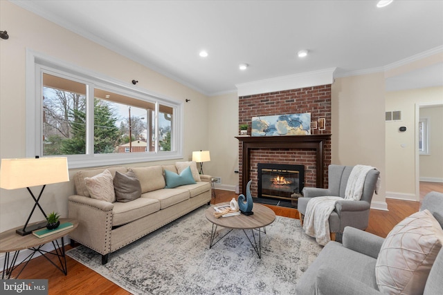 living area featuring a fireplace, wood finished floors, visible vents, and crown molding