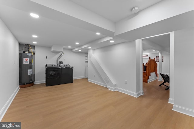 finished below grade area featuring washer and clothes dryer, recessed lighting, water heater, light wood-style floors, and stairs