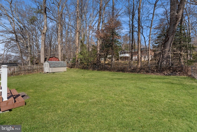 view of yard featuring a storage shed, fence, and an outbuilding