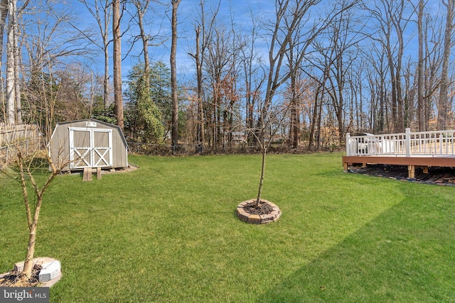 view of yard featuring an outbuilding, fence, a deck, and a storage unit