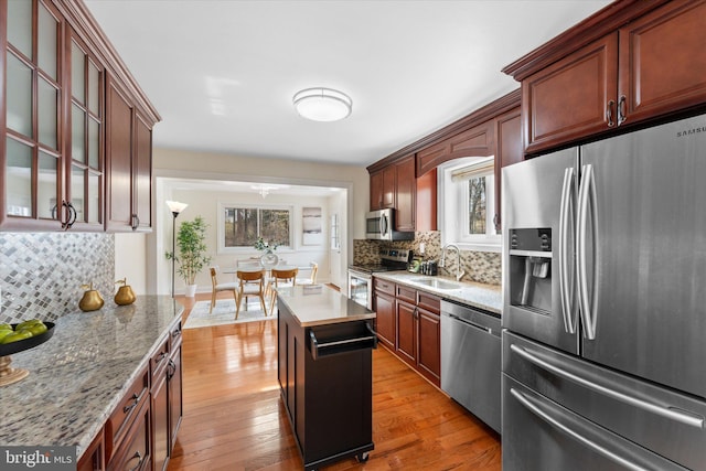 kitchen featuring appliances with stainless steel finishes, hardwood / wood-style flooring, a sink, and tasteful backsplash